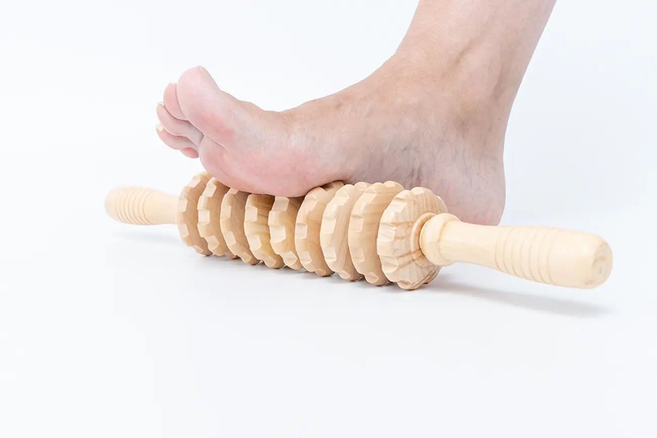 foot resting on wooden massage roller