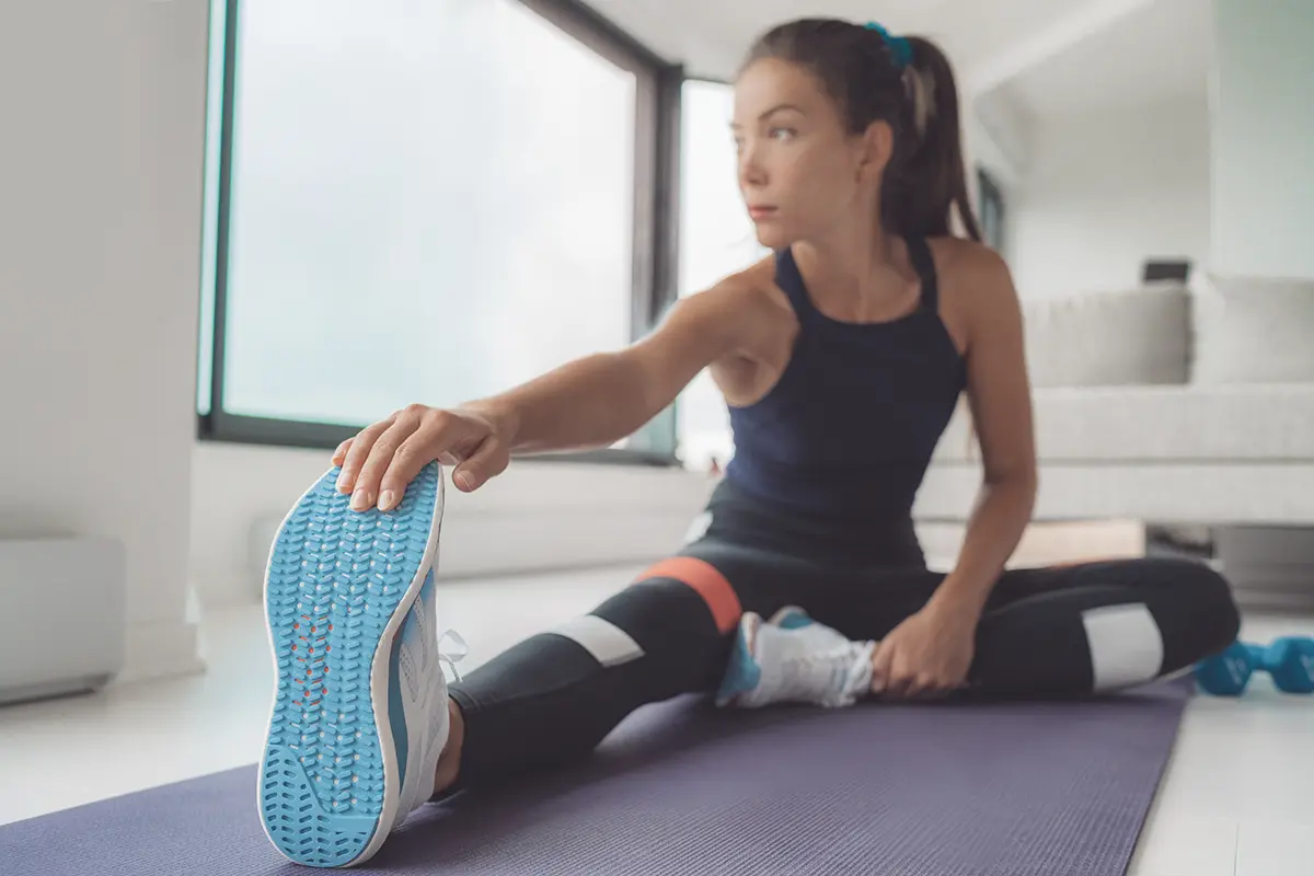 woman doing pilates workout using elastic strap pulling with arms for shoulder training on yoga mat indoors woman doing pilates workout using elastic strap pulling with arms for shoulder training on yoga mat indoors